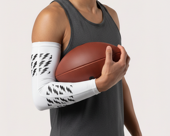 Man holding a basketball with a white arm sleeve on a plain background
