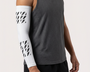 Man wearing a gray tank top and black shorts with a white arm sleeve featuring black patterns on a light gray background.