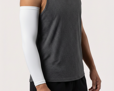 Man wearing a gray tank top and black shorts with a white arm sleeve on a plain background